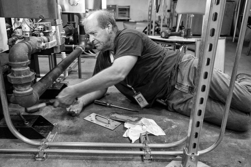 A town worker working in a garage on something mechanical.